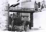 Siamo negli anni della ricostruzione 1946/7/8, si costruisce il nuovo ponte a monte del vecchio di circa 200mt,.sulle fondamenta del quale, è costruita la passerella pedonale. Nella foto si vede il muraglione e la passerella di legno. Per far posto al ponte saranno rimosse le macerie di alcune case
Gli uomini ritratti in questa foto sono: con la bicicletta Enzo Cecchi presidente della cooperativa di ricostruzione, Terzani Enzo, e dietro sulla sinistra Giulio Casalini.